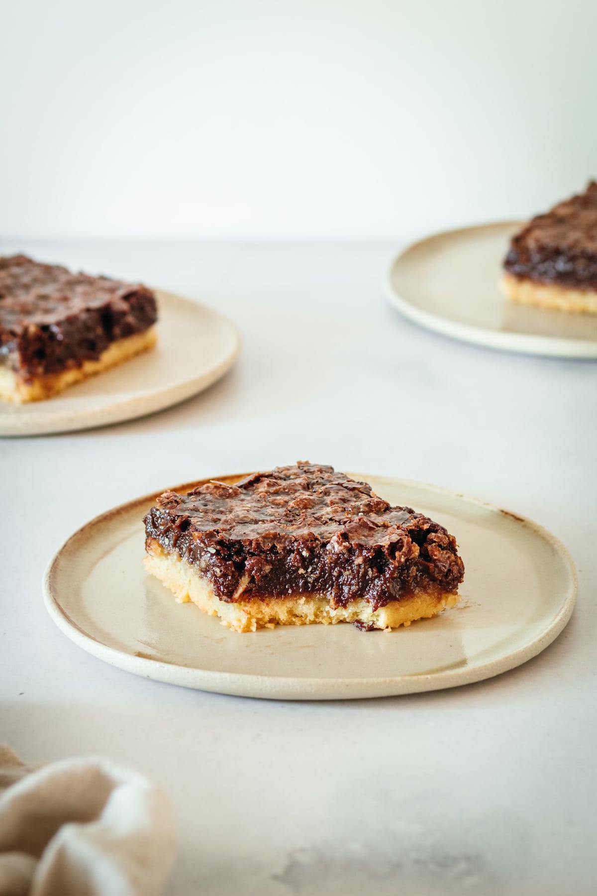 Three plates of pecan pie bars, with a bite taken out of one