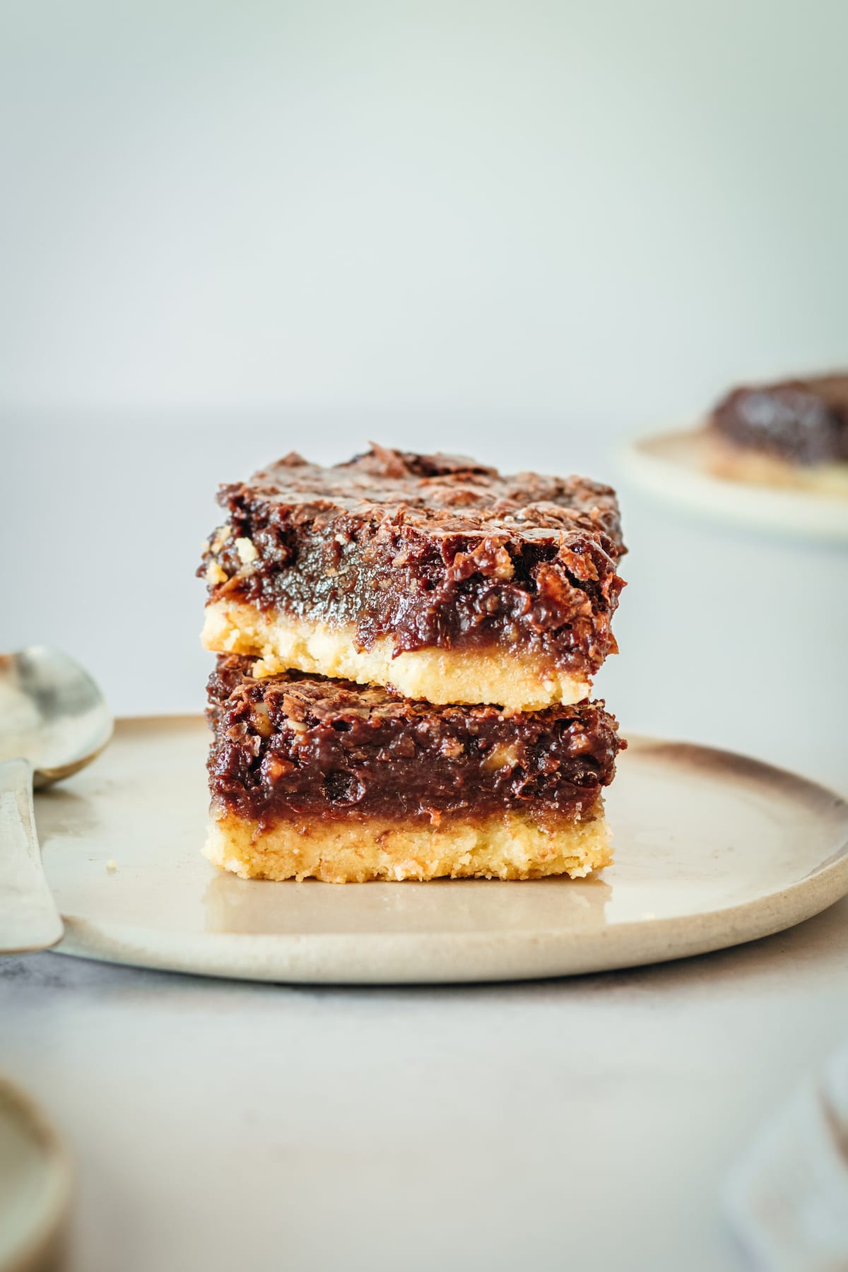 Two chocolate pecan pie bars stacked on plate