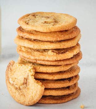 Stack of cinnamon roll cookies with glass milk bottle in background