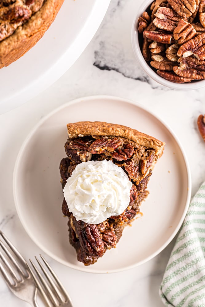 overhead view of a slice of Deep-Dish Pecan Pie topped with whipped cream