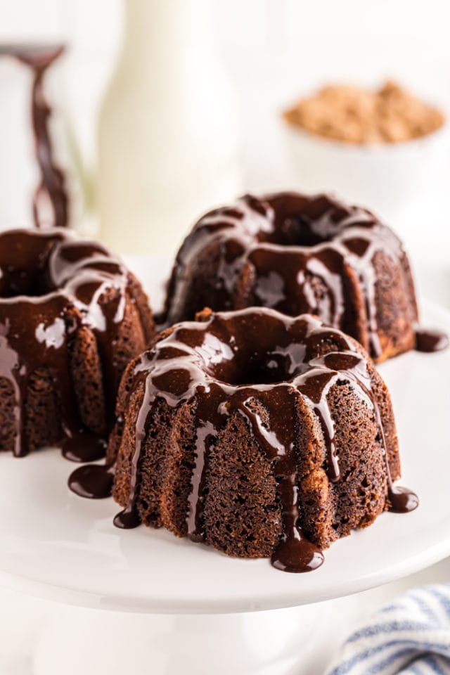 three Mini Chocolate Bundt Cakes on a white pedestal