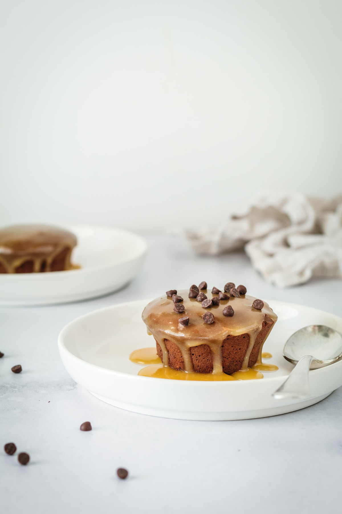 Two mini pound cakes on white plates, topped with chocolate chips