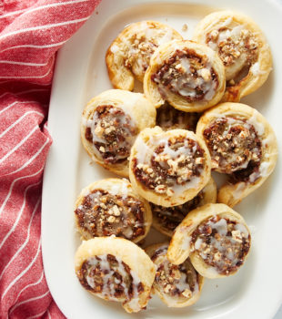 overhead view of Apple Butter Pinwheels on a large white plate next to a red and white striped kitchen towel