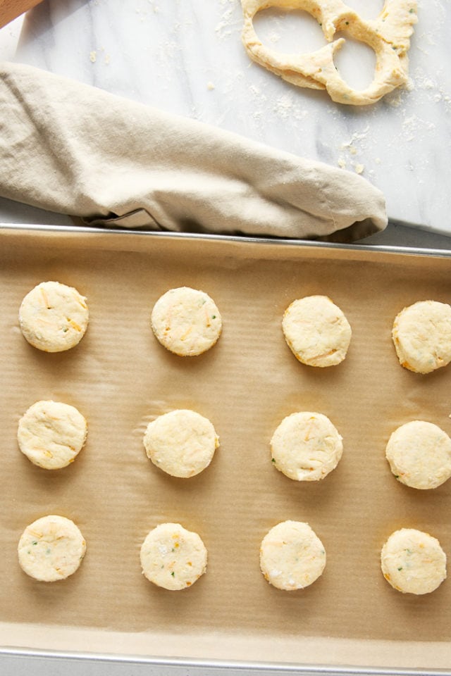 overhead view of Cheddar and Chive Cornmeal Biscuits on a parchment-lined baking sheet ready to be baked