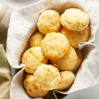 overhead view of Cheddar and Chive Cornmeal Biscuits in a towel-lined basket