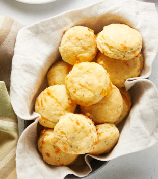 overhead view of Cheddar and Chive Cornmeal Biscuits in a towel-lined basket