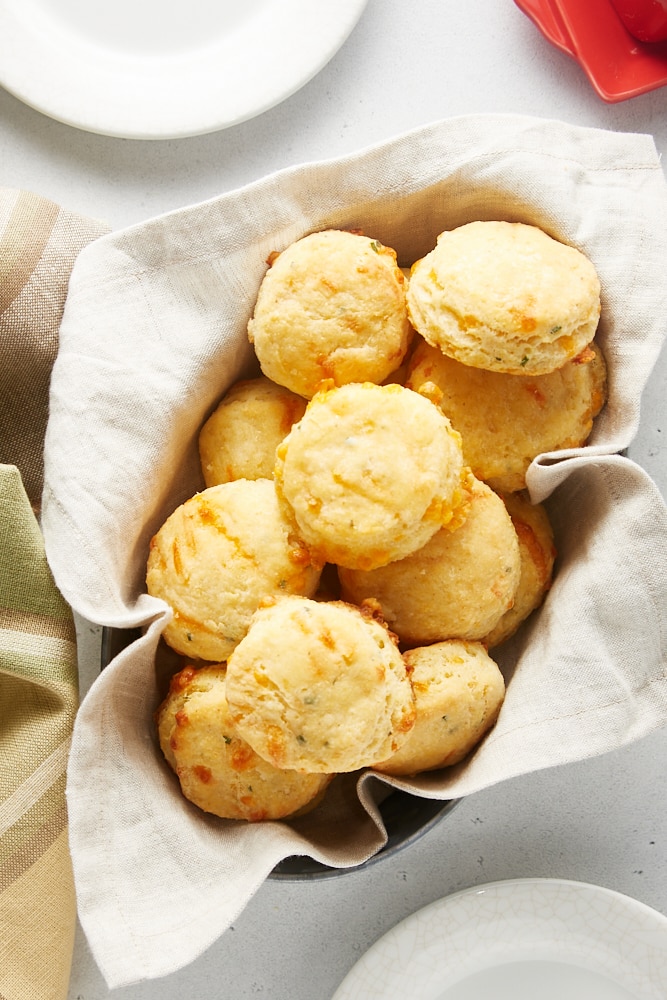 overhead view of Cheddar and Chive Cornmeal Biscuits in a towel-lined basket