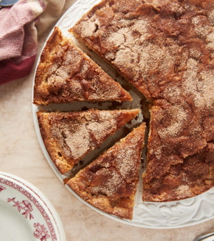 overhead view of Cinnamon Pear Cake partially sliced on a white cake plate