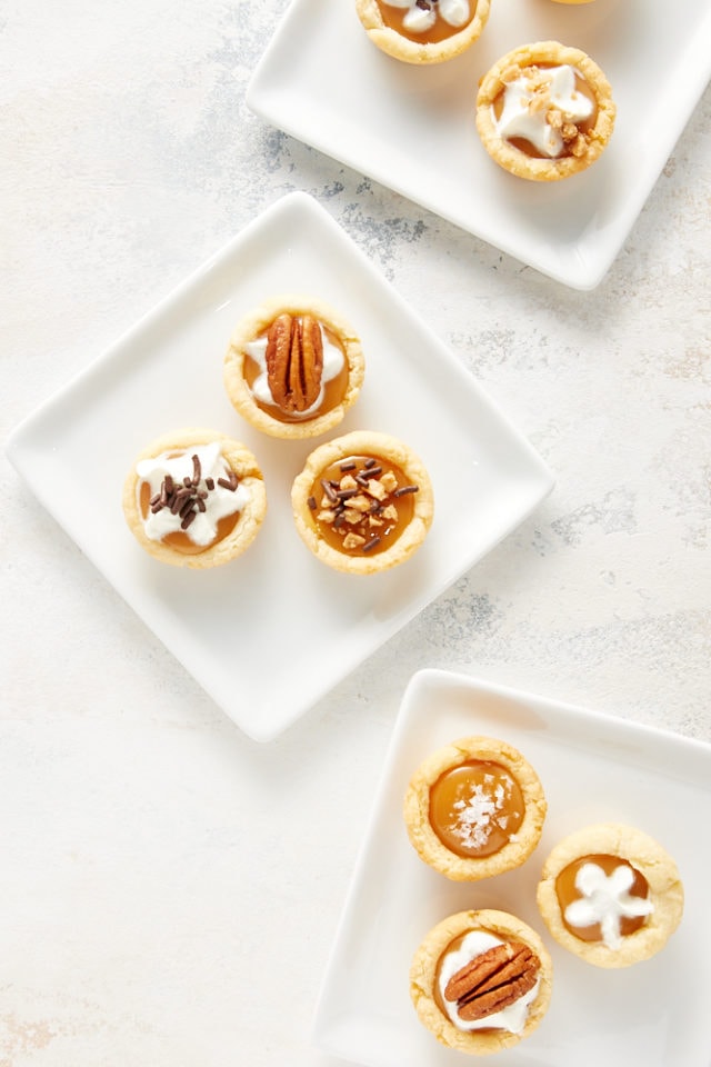 overhead view of Mini Caramel Tarts on square white plates