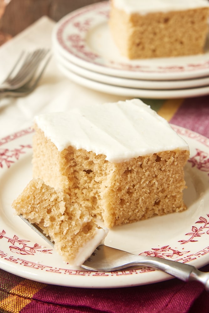 Slice of spice cake with a bite on a fork on a red floral-rimmed plate