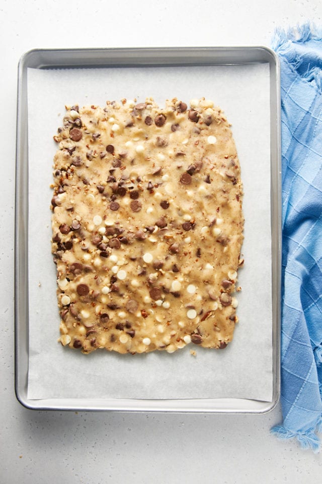 overhead view of Triple Chocolate Chip Cookie Brittle cookie dough shaped into a rectangle on a lined baking sheet