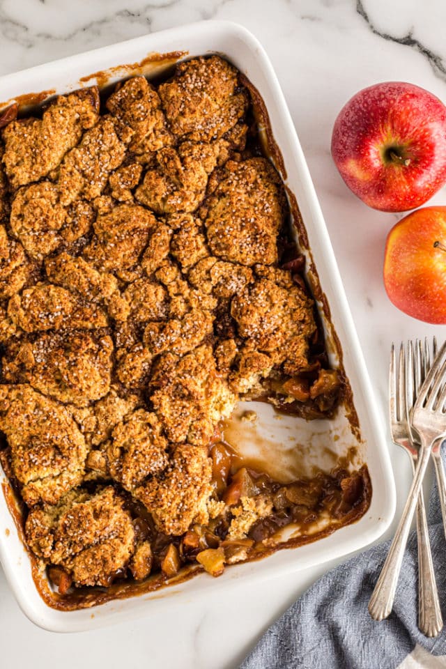 overhead view of Brown Sugar Apple Cobbler in a white rectangular baking pan; one corner of the cobbler is missing from the pan
