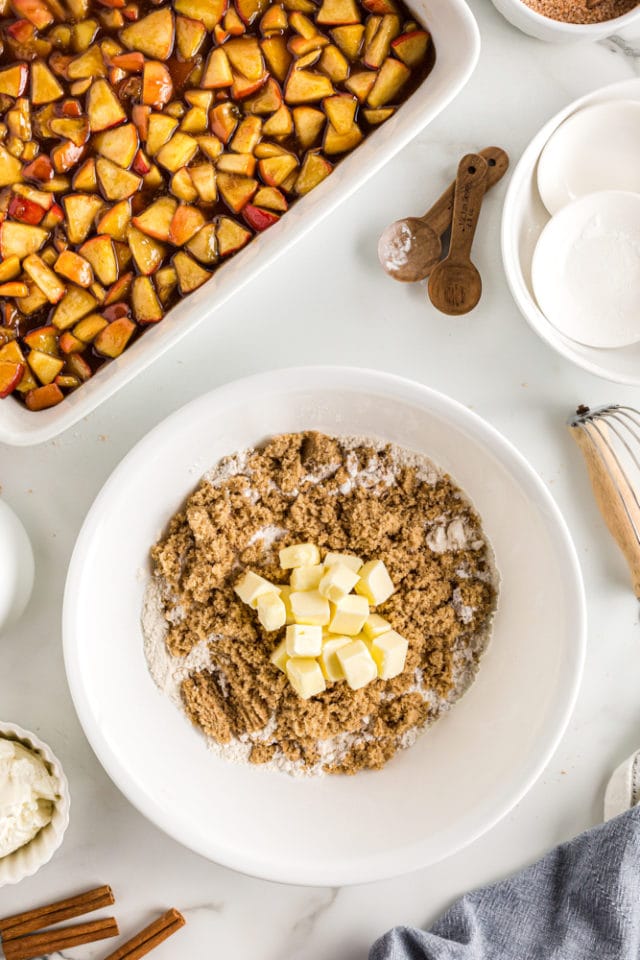 overhead view of dry ingredients and butter in a white mixing bowl for apple cobbler topping