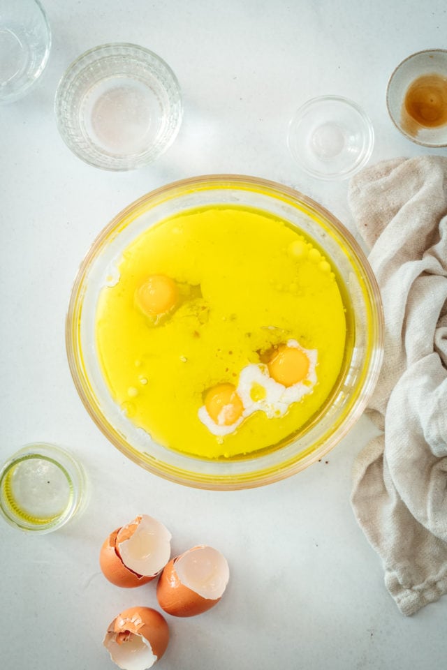 Overhead view of eggs being incorporated into wet cake ingredients