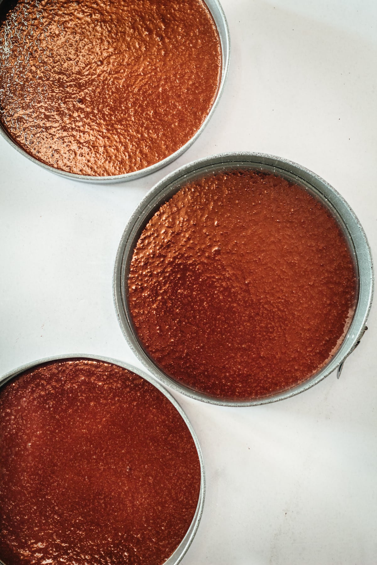 Overhead view of 3 round cake pans with chocolate cake inside