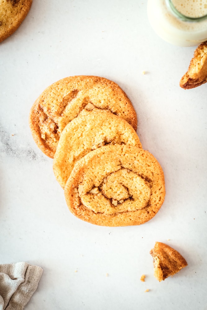 Three cinnamon roll cookies on marble slab.