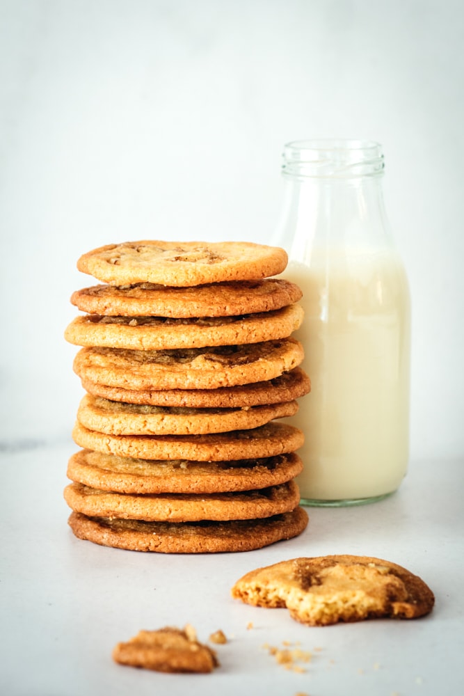 Stack of cinnamon roll cookies with a glass milk bottle.