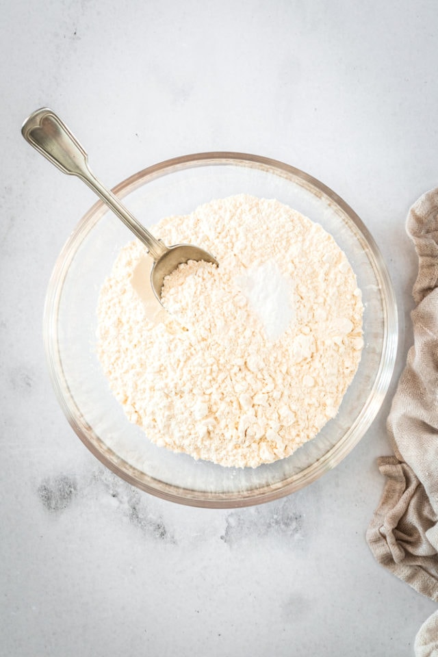 Overhead shot of dry ingredients for cookies in glass bowl with spoon