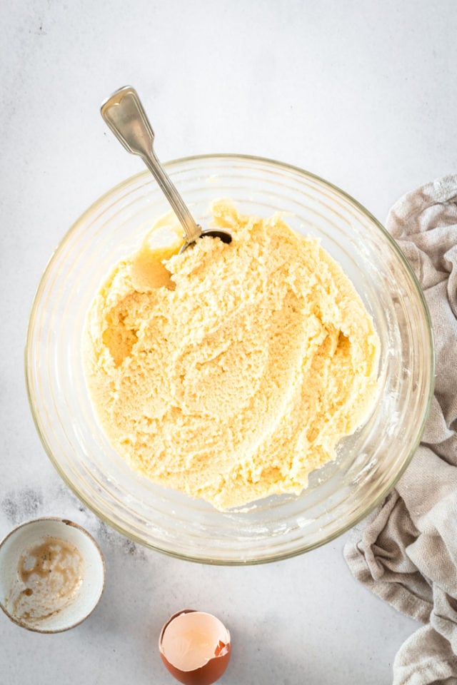 Sugar cookie dough in a glass bowl with a spoon.