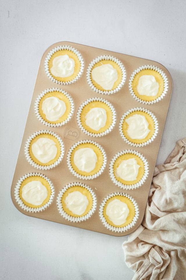 Overhead view of cream cheese muffins in baking tin before topping with nuts and baking