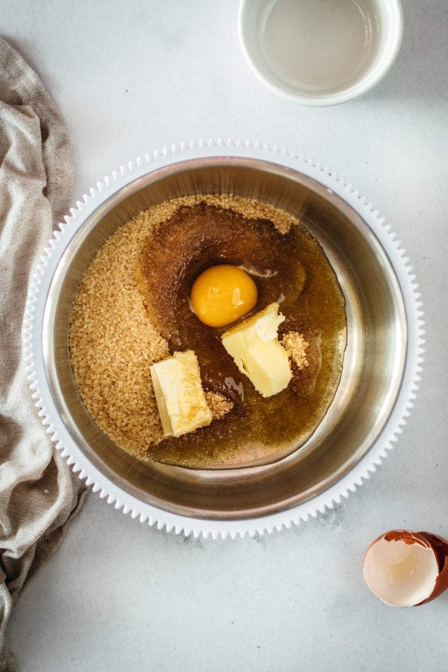 Overhead view of brown sugar, butter, and egg in a mixing bowl.