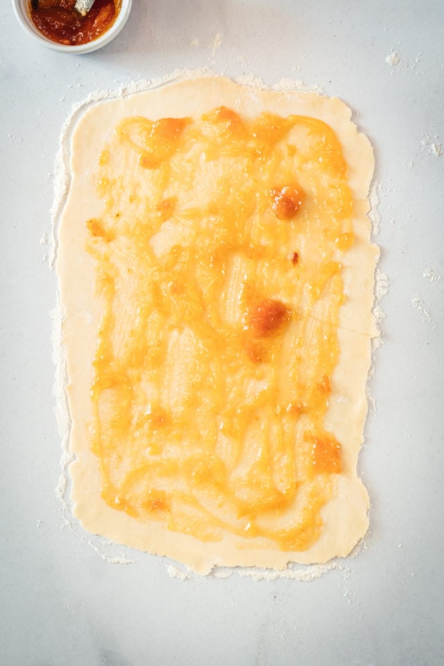 Rectangle of rugelach dough topped with apricot preserves