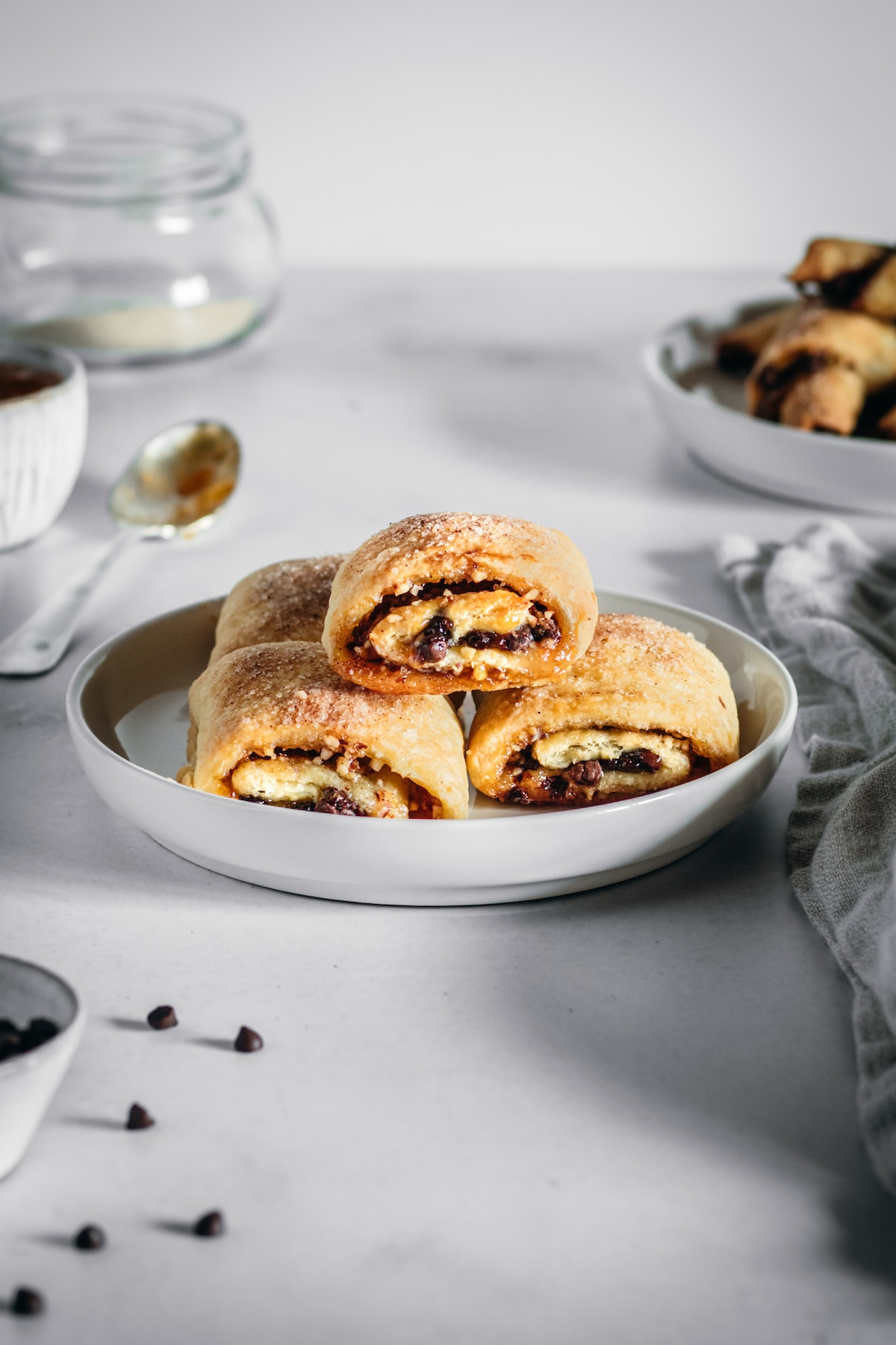 Rectangle rugelach stacked onto a plate with ingredients scattered in background