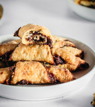 Rugelach piled onto a white plate with high edges