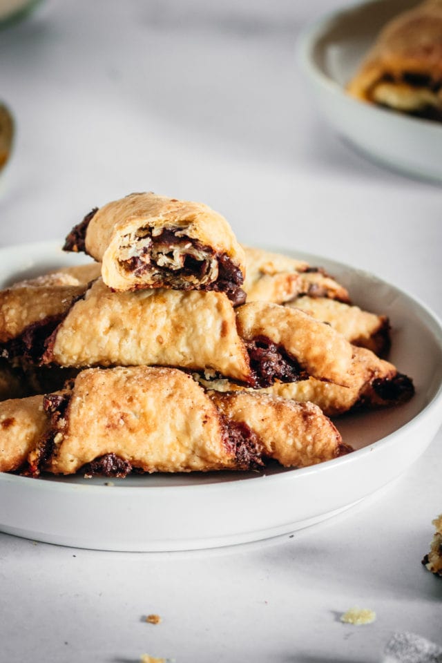 Rugelach piled onto a white plate with high edges