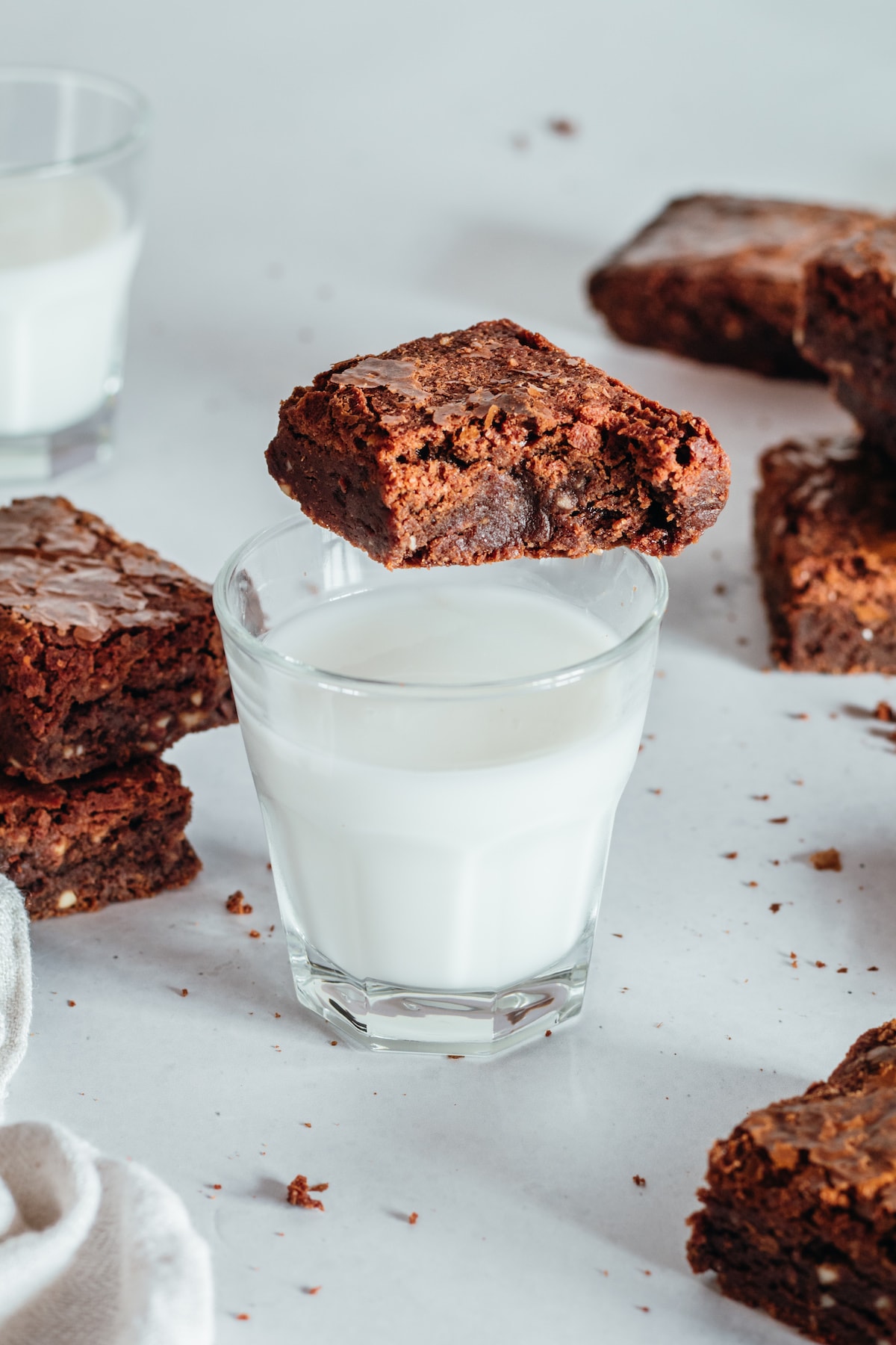 Cup of milk with brownie resting on edge and additional brownies in background