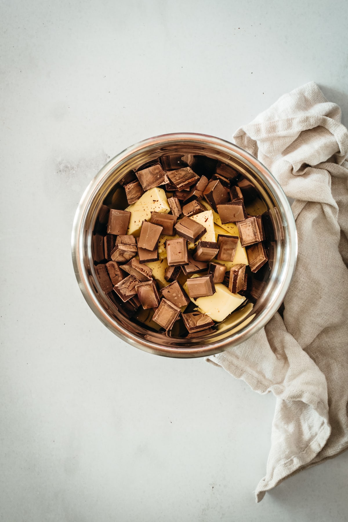 Overhead view of chocolate pieces and butter in metal bowl