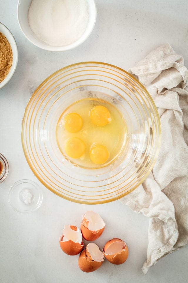 Overhead view of 4 eggs cracked into glass mixing bowl