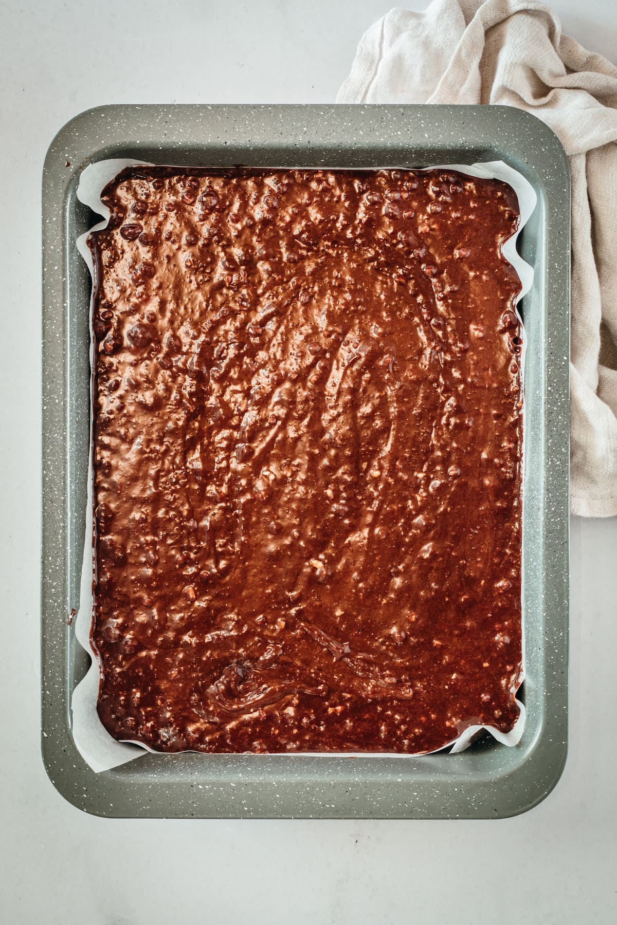 Overhead view of brownie batter in parchment-lined pan