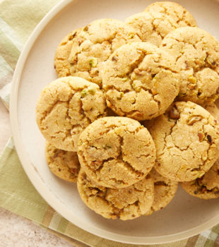 overhead view of Brown Butter Pistachio Cookies piled on a beige plate