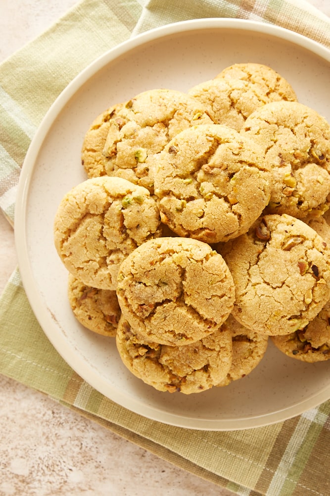 overhead view of Brown Butter Pistachio Cookies piled on a beige plate