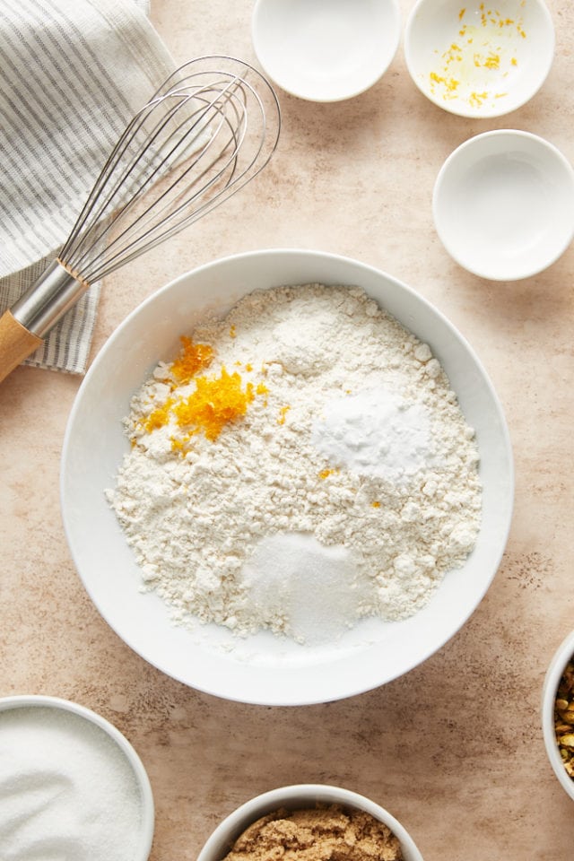 overhead view of flour, baking soda, salt, and orange zest in a white bowl