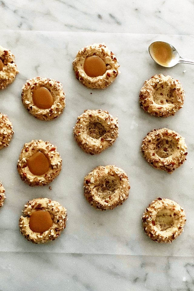 overhead view of pecan thumbprint cookies, some filled with caramel
