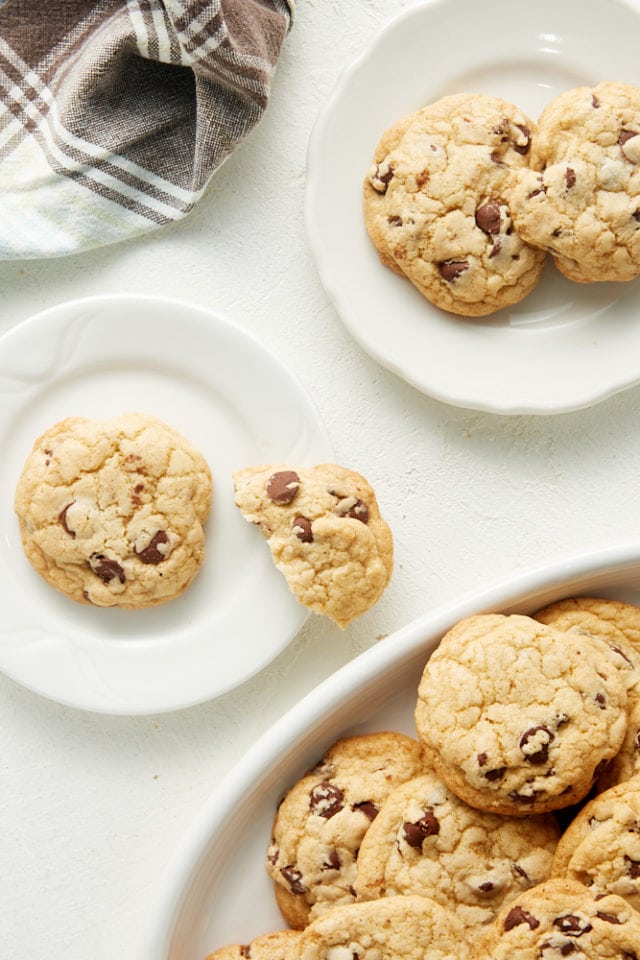 overhead view of chocolate chip cookies on white plates and a white serving tray