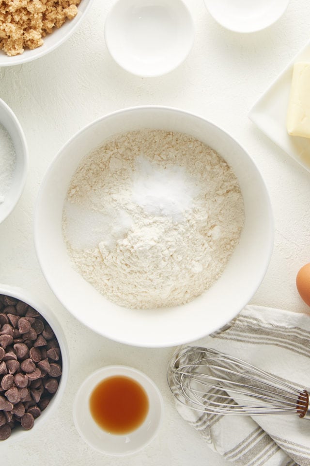 overhead view of flour, baking soda, and salt in a white mixing bowl