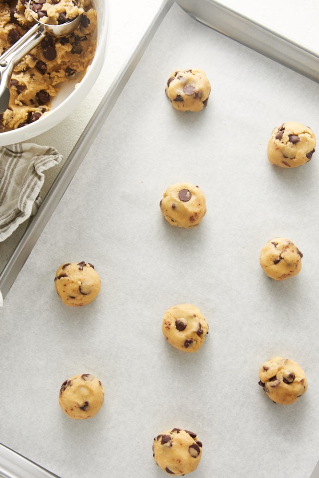 overhead view of unbaked Chewy Chocolate Chip Cookie dough on a parchment-lined baking sheet