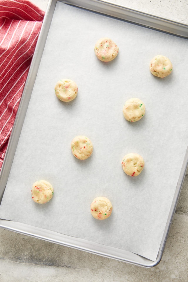 Overhead view of flattened sugar cookie dough on a parchment-lined baking sheet.