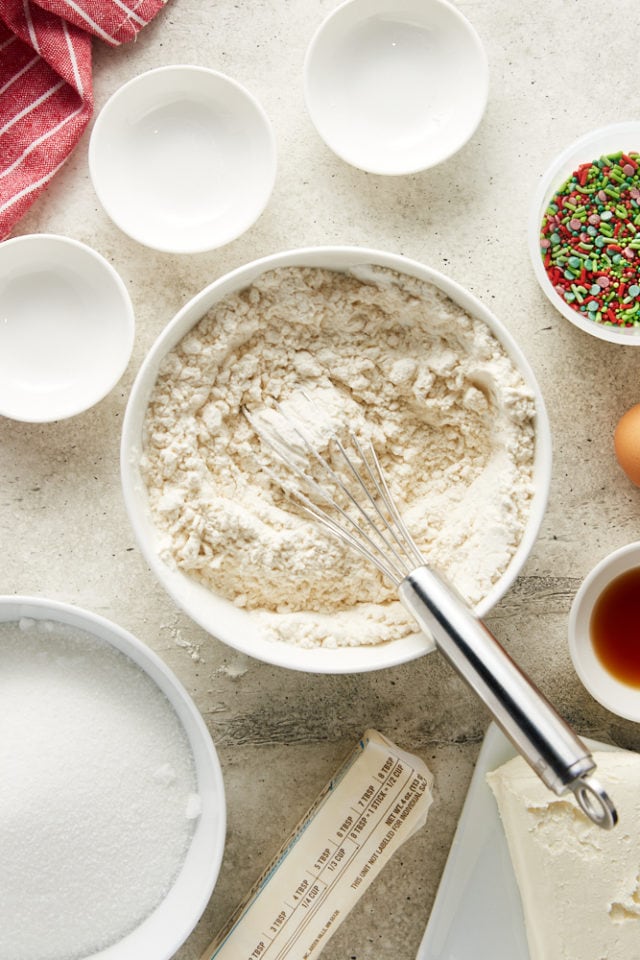 Overhead view of mixed dry ingredients for sugar cookies in a white mixing bowl.