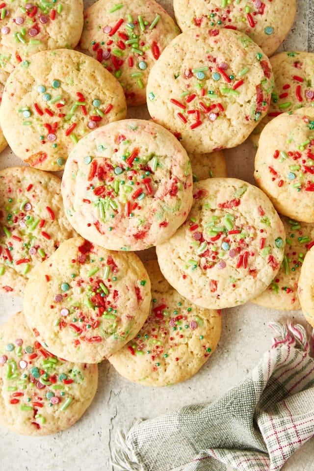 overhead view of Soft Christmas Sprinkle Sugar Cookies scattered on a light gray surface