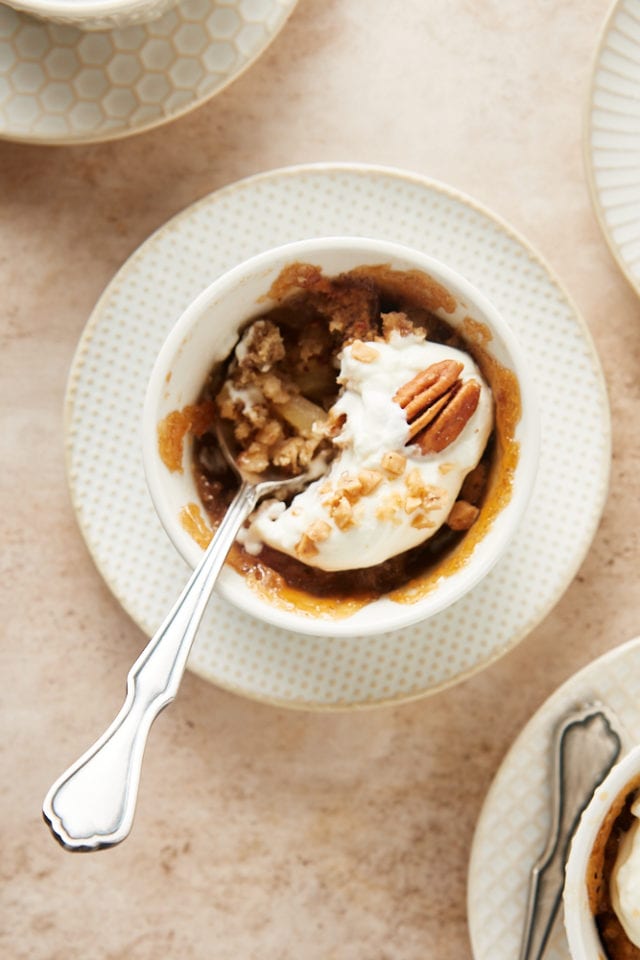 overhead view of a Ginger Pear Pudding Cake with a bite missing and a spoon resting in the ramekin