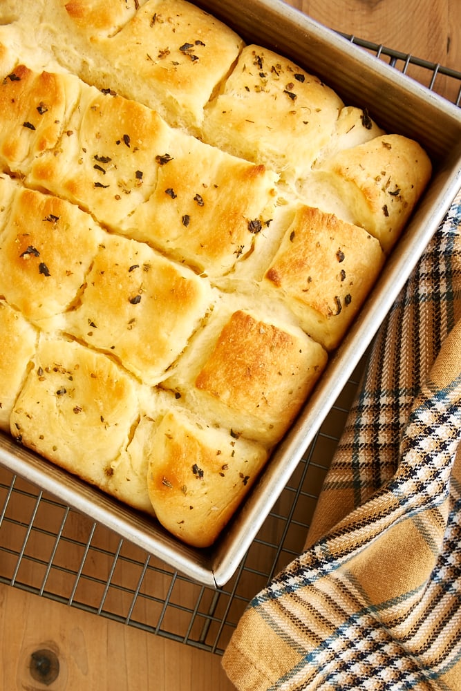 overhead view of Herbed Dinner Rolls in a square baking pan sitting on a wire rack