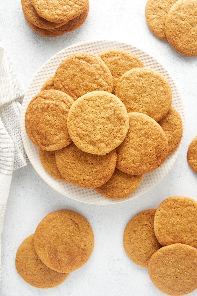 overhead view of Maple Ginger Cookies on a white plate with more cookies scattered around