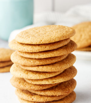 stack of Maple Ginger Cookies with more cookies surrounding it and a light blue-green mug