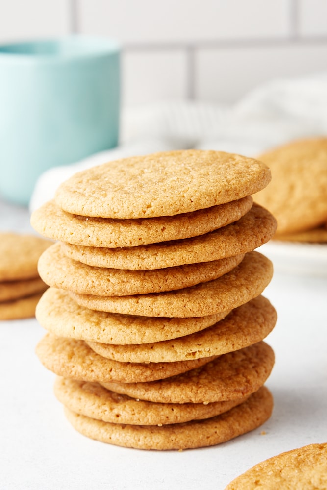 stack of Maple Ginger Cookies with more cookies surrounding it and a light blue-green mug