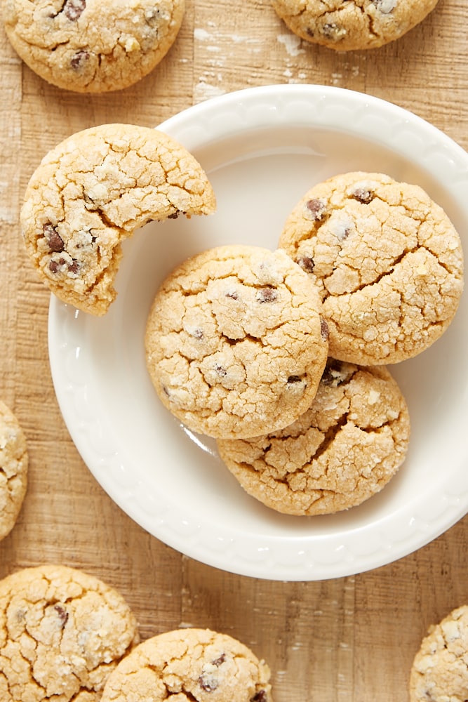 Overhead view of peanut butter crinkle cookies on a white plate with more cookies surrounding.