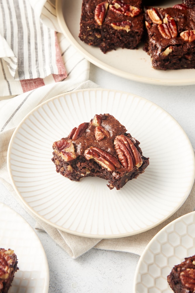 a Pecan Lovers' Brownie with a bite missing on a white and beige plate